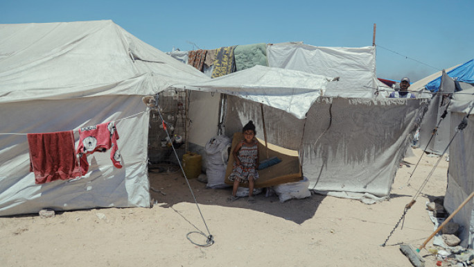 A young Palestinian girl looks into the camera as displaced Palestinians live in temporary tents set up near demolished buildings as displacement crisis worsens in Gaza, Palestinian territories on May 29, 2025.